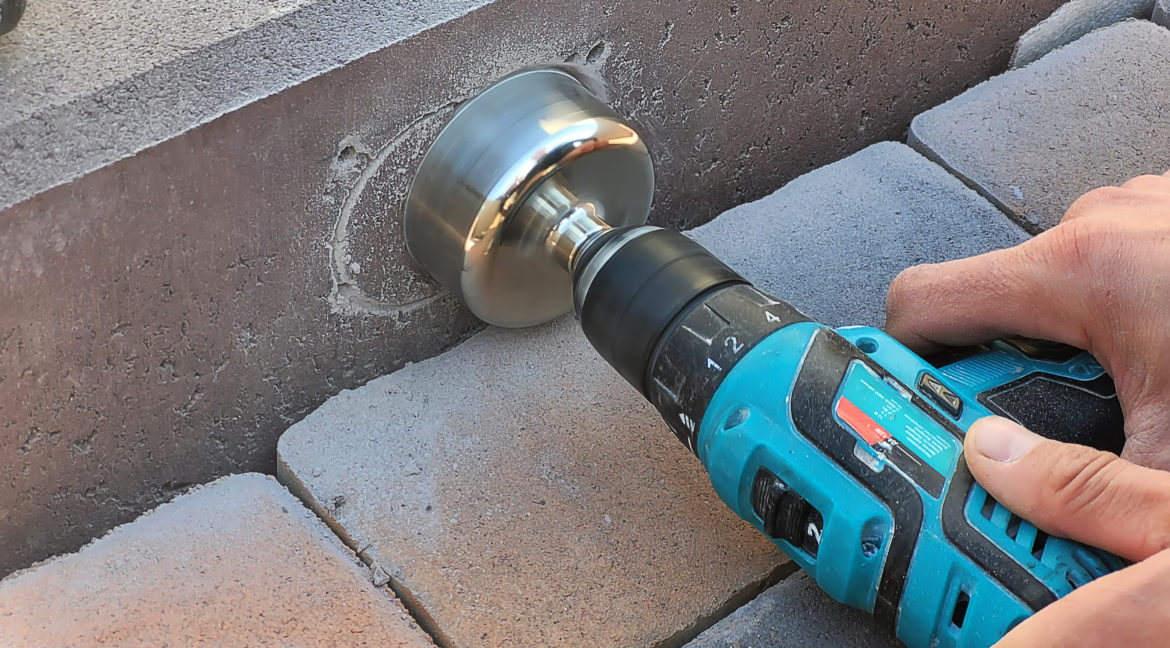 drilling a concrete curb to install the luminaire.