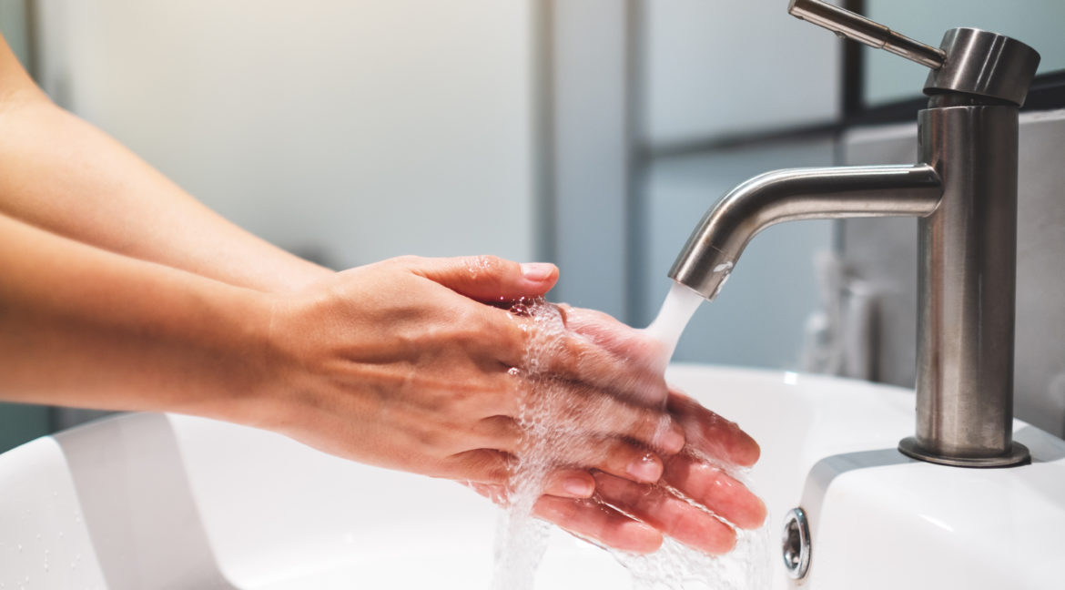 Woman cleaning and washing hands under the faucet in bathroom