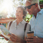 Older adults planning relocation with a map in a sunny park, representing Ventura County 2025 downsizing and retirement living.