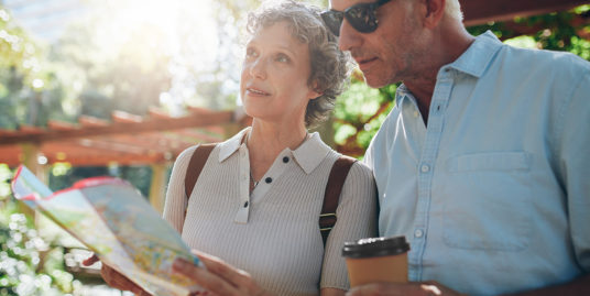 Older adults planning relocation with a map in a sunny park, representing Ventura County 2025 downsizing and retirement living.